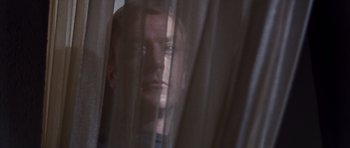 Movie still from “Gambit” (1966), directed by Ronald Neame – A person looking out a window; Close Up shot, Low angle