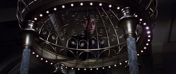 Movie still from “Gambit” (1966), directed by Ronald Neame – A man standing in front of a metal gate; Medium shot, Low angle