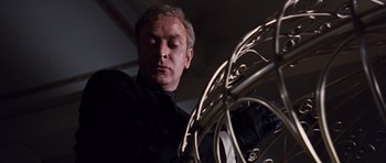 Movie still from “Gambit” (1966), directed by Ronald Neame – A person looking at a piece of metal; Close Up shot, Low angle