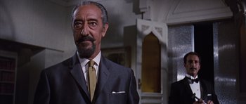 Movie still from “Gambit” (1966), directed by Ronald Neame – An older man wearing a suit and tie in a room; Close Up shot, Low angle