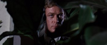 Movie still from “Gambit” (1966), directed by Ronald Neame – A person wearing a suit and tie; Close Up shot, Low angle