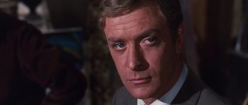 Movie still from “Gambit” (1966), directed by Ronald Neame – A person wearing a suit and tie; Close Up shot, Low angle