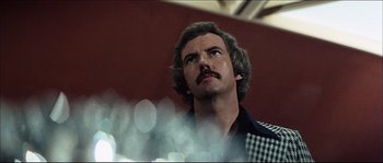 Movie still from “Game of Death” (1978), directed by Robert Clouse – A person with a mustache looking up; Close Up shot, Low angle