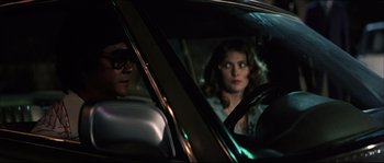 Movie still from “Game of Death” (1978), directed by Robert Clouse – A man and a woman sitting in the drivers seat of a car at night; Close Up shot, Over the shoulder angle