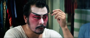 Movie still from “Game of Death” (1978), directed by Robert Clouse – A man is putting makeup on another man's face; Close Up shot, Over the shoulder angle