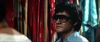 Movie still from “Game of Death” (1978), directed by Robert Clouse – A man wearing a pair of glasses and a blue shirt; Close Up shot, Low angle