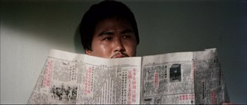 Movie still from “Game of Death” (1978), directed by Robert Clouse – A man is reading a newspaper in front of his face; Close Up shot, Low angle