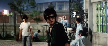 Movie still from “Game of Death” (1978), directed by Robert Clouse – A young man wearing sunglasses and a black jacket; Medium shot, Low angle