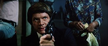 Movie still from “Game of Death” (1978), directed by Robert Clouse – A person holding a gun in a room; Close Up shot, Low angle