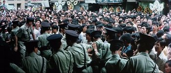Movie still from “Game of Death” (1978), directed by Robert Clouse – A large group of men in green uniforms and black hats; Wide shot, High angle