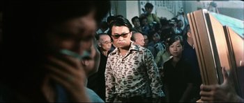 Movie still from “Game of Death” (1978), directed by Robert Clouse – A group of people that are standing in a room; Medium shot, Over the shoulder angle