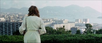 Movie still from “Game of Death” (1978), directed by Robert Clouse – A woman in a white robe looking out over a city; Wide shot, Over the shoulder angle
