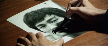 Movie still from “Game of Death” (1978), directed by Robert Clouse – A person is drawing a picture of a man; Extreme Close Up shot, High angle