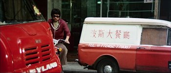 Movie still from “Game of Death” (1978), directed by Robert Clouse – A man riding a motorcycle down a street next to a van; Wide shot, Low angle