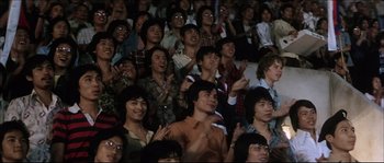 Movie still from “Game of Death” (1978), directed by Robert Clouse – A group of people sitting in a crowd clapping; Medium shot, High angle
