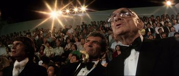 Movie still from “Game of Death” (1978), directed by Robert Clouse – Two men in suits and bow ties in front of an audience; Medium shot, Low angle
