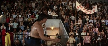 Movie still from “Game of Death” (1978), directed by Robert Clouse – A man holding a rope in front of an audience; Wide shot, Low angle