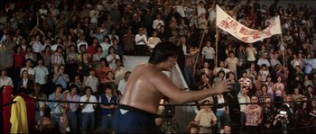Movie still from “Game of Death” (1978), directed by Robert Clouse – A man is standing in front of a crowd; Wide shot, Low angle