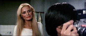 Movie still from “Game of Death” (1978), directed by Robert Clouse – A woman with long blonde hair standing in front of a man; Close Up shot, Over the shoulder angle