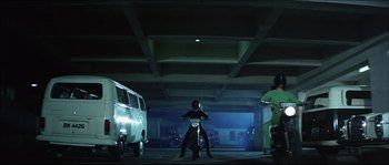 Movie still from “Game of Death” (1978), directed by Robert Clouse – A man riding a motorcycle in a parking garage; Wide shot, Low angle