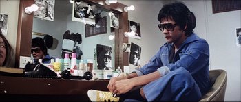 Movie still from “Game of Death” (1978), directed by Robert Clouse – A man sitting in front of a mirror in a room; Medium shot, High angle