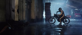 Movie still from “Game of Death” (1978), directed by Robert Clouse – A man riding a motorcycle down the middle of a street; Wide shot, Low angle