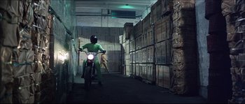 Movie still from “Game of Death” (1978), directed by Robert Clouse – A person riding a motorcycle in a warehouse; Wide shot, High angle