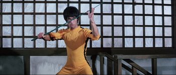 Movie still from “Game of Death” (1978), directed by Robert Clouse – A man in a yellow and black outfit holding a bow and arrow; Medium shot, Low angle