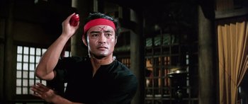 Movie still from “Game of Death” (1978), directed by Robert Clouse – A man with a red bandage on his head; Medium shot, Low angle