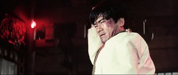 Movie still from “Game of Death” (1978), directed by Robert Clouse – A man with a bruise on his face and shoulder; Close Up shot, Low angle