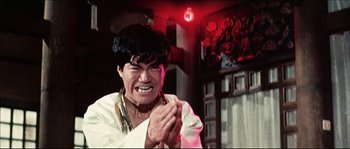 Movie still from “Game of Death” (1978), directed by Robert Clouse – A man in a white shirt clapping his hands; Medium shot, Low angle