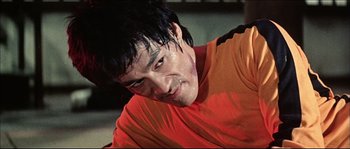 Movie still from “Game of Death” (1978), directed by Robert Clouse – A person wearing a red and orange shirt; Close Up shot, Low angle