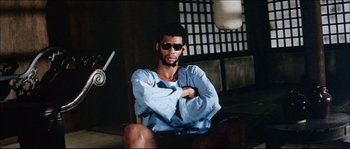 Movie still from “Game of Death” (1978), directed by Robert Clouse – A man sitting on a chair with his arms crossed; Medium shot, Low angle