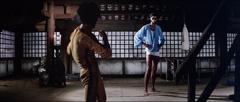 Movie still from “Game of Death” (1978), directed by Robert Clouse – Two men are practicing martial arts in an asian setting; Wide shot, Low angle
