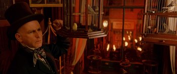 Movie still from “Gangs of New York” (2002), directed by Martin Scorsese – A person holding a bird in a cage in front of a fireplace; Medium shot, Over the shoulder angle