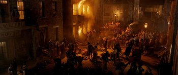 Movie still from “Gangs of New York” (2002), directed by Martin Scorsese – A group of people standing in front of a building on fire; Extreme Wide shot, High angle