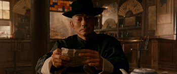 Movie still from “Gangs of New York” (2002), directed by Martin Scorsese – A man wearing a black hat holding a piece of paper; Close Up shot, Low angle