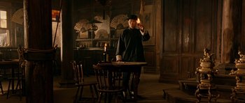 Movie still from “Gangs of New York” (2002), directed by Martin Scorsese – A man standing at a table holding a candle; Wide shot, Low angle
