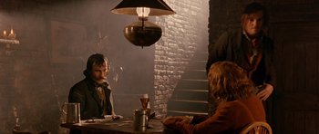 Movie still from “Gangs of New York” (2002), directed by Martin Scorsese – Two people sitting at a table in front of a lamp; Medium shot, Over the shoulder angle