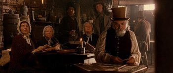 Movie still from “Gangs of New York” (2002), directed by Martin Scorsese – A group of people sitting at a table with a lit candle; Medium shot, Low angle
