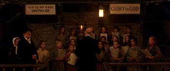 Movie still from “Gangs of New York” (2002), directed by Martin Scorsese – A group of young children singing in front of an older man; Wide shot, Low angle