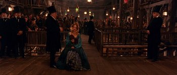 Movie still from “Gangs of New York” (2002), directed by Martin Scorsese – A woman sitting on the ground in front of a group of people; Wide shot, High angle