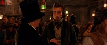 Movie still from “Gangs of New York” (2002), directed by Martin Scorsese – A man wearing a top hat and a bow tie talking to another man wearing a suit; Close Up shot, Over the shoulder angle