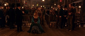 Movie still from “Gangs of New York” (2002), directed by Martin Scorsese – A woman sitting on the ground in front of a group of people; Wide shot, High angle