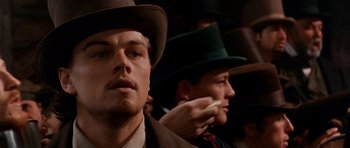 Movie still from “Gangs of New York” (2002), directed by Martin Scorsese – A man in a suit and a green hat is holding a cell phone to his ear; Close Up shot, Low angle