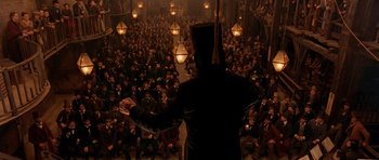 Movie still from “Gangs of New York” (2002), directed by Martin Scorsese – A crowd of people sitting and standing in front of a man; Wide shot, High angle