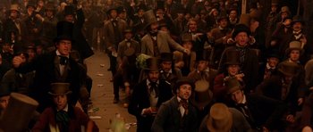 Movie still from “Gangs of New York” (2002), directed by Martin Scorsese – A group of men in top hats are walking down the street; Wide shot, High angle