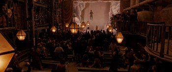 Movie still from “Gangs of New York” (2002), directed by Martin Scorsese – A crowd of people sitting in front of stage lights; Extreme Wide shot, High angle