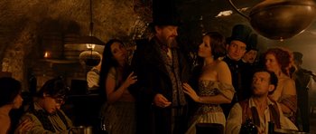 Movie still from “Gangs of New York” (2002), directed by Martin Scorsese – A man and two women are standing in a dark room; Medium shot, Over the shoulder angle
