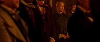 Movie still from “Gangs of New York” (2002), directed by Martin Scorsese – A man standing next to a group of people in a room; Medium shot, Over the shoulder angle